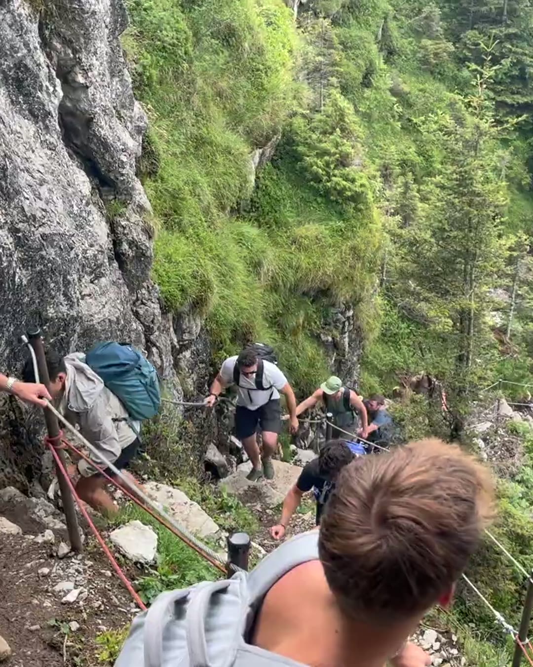 Refined Path travelers climbing a cable-lined alpine trail in the Swiss Alps